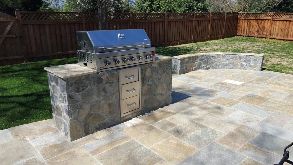 backyard patio with gas grill and curved stone bench