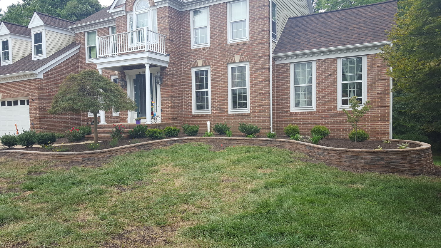 large house with raised planting bed help up by short undulating retaining wall