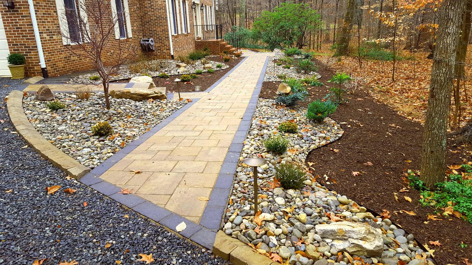 walkway from driveway to front door crossing landscape of mulch and stone planting beds